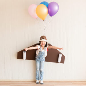 young girl with cardboard wings on and balloons attached to her back