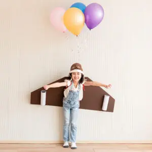 young girl with cardboard wings on and balloons attached to her back