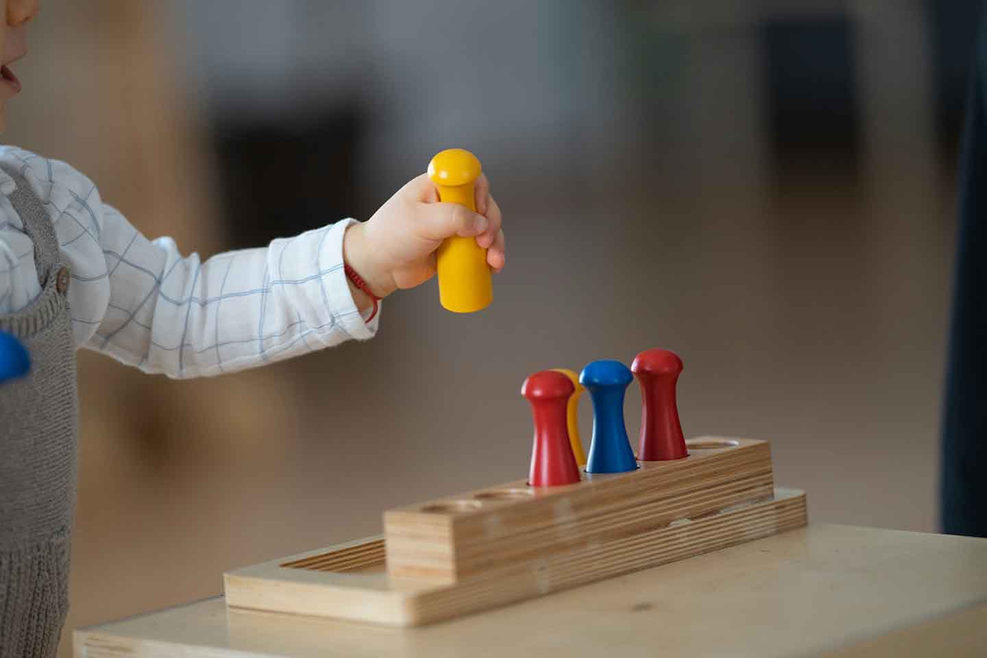 child with toy in hand playing at table