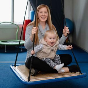 Stephanie Vogler and daughter sitting in swing in OT office