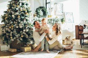 child with parents in front of Christmas tree
