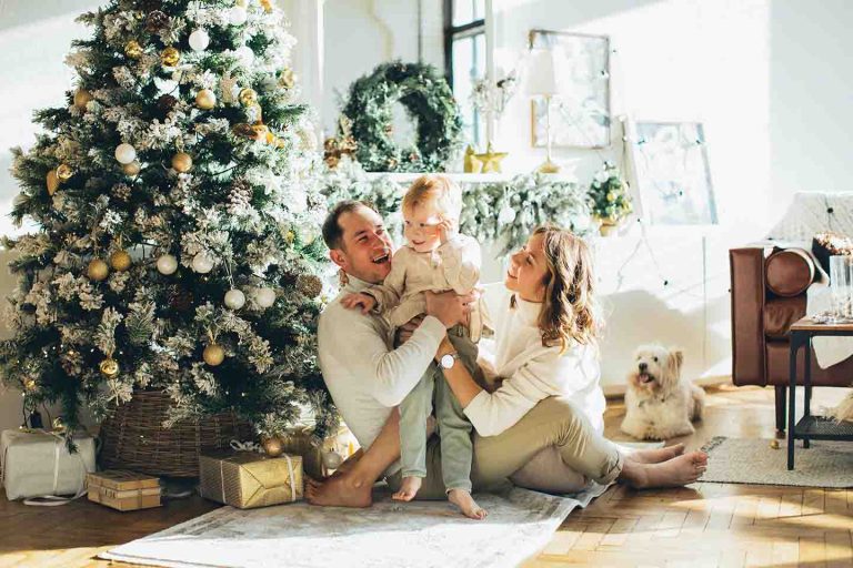 child with parents in front of Christmas tree